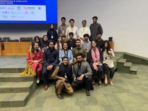 Students gather around a panel of speakers in front of a projection screen